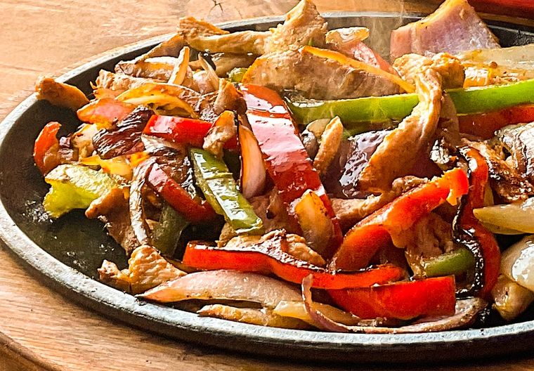 Chicken fajitas on the cast iron skillet, peppers and red onion still steaming.
